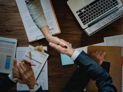 Two white collar workers shaking hands over a mutually beneficial business deal